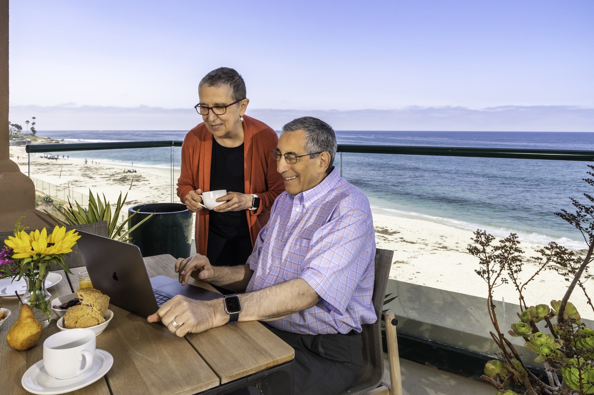 Couple on their balcony with laptop	